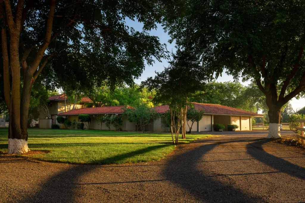 Front elevation of the Mediterranean residence with tile roof and mature landscaping.