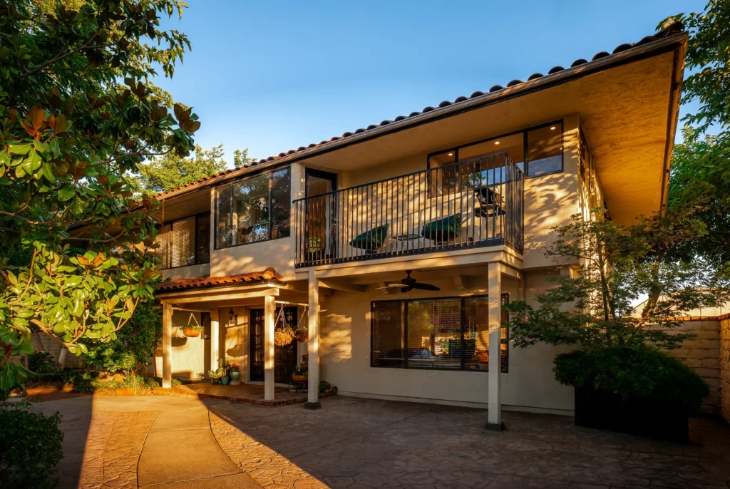 Rear elevation of the Mediterranean residence with covered patio and mature landscaping.