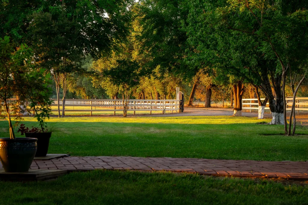 Manicured lawn and white three-rail fencing between the residence and horse pastures.