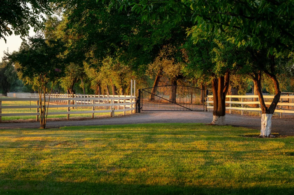 Sixteen-foot private entry gate with classic white ranch fencing.